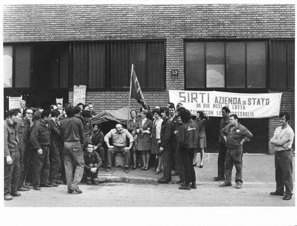 Occupazione della fabbrica Sirti - Tenda dei lavoratori davanti all'ingresso della fabbrica - Operai con abito da lavoro - Striscione - Cartelli - Bandiera Fim, Fiom, Uilm