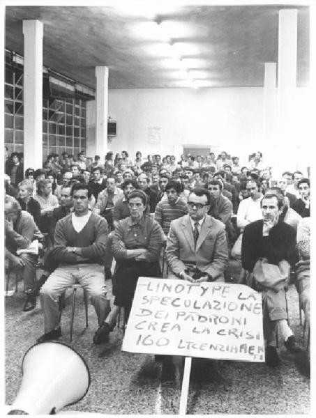 Fabbrica - Interno - Assemblea per la Chatillon - Panoramica sulla sala - Platea con lavoratori - Cartello