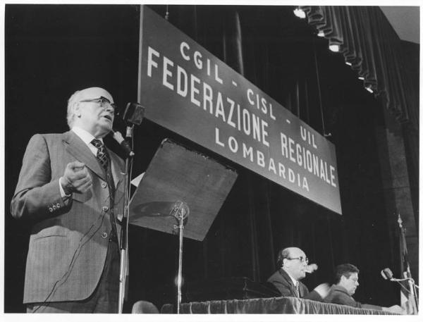 Teatro San Babila - Interno - Assemblea di costituzione della federazione regionale Cgil, Cisl, Uil - Tavolo della presidenza con Lauro Casadio - Oratore al microfono - Parola d'ordine