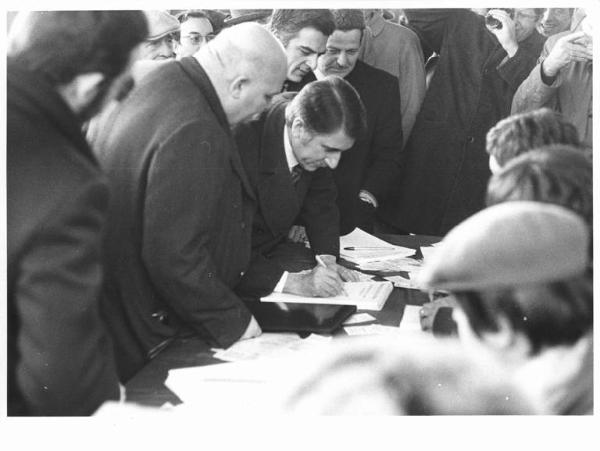 Manifestazione per la pace in Vietnam - Piazza Sempione - Banchetto raccolta firme - Aldo Aniasi firma l'adesione alla manifestazione, al suo fianco Giulio Polotti