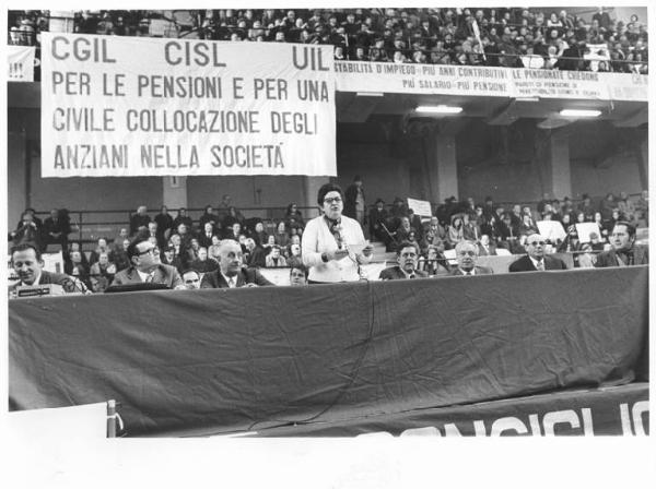 Manifestazione nazionale Cgil, Cisl e Uil per le pensioni - Palalido - Interno - Comizio - Palco - Tavolo della presidenza con oratrice al microfono, al suo fianco Lauro Casadio - Parola d'ordine - Striscioni