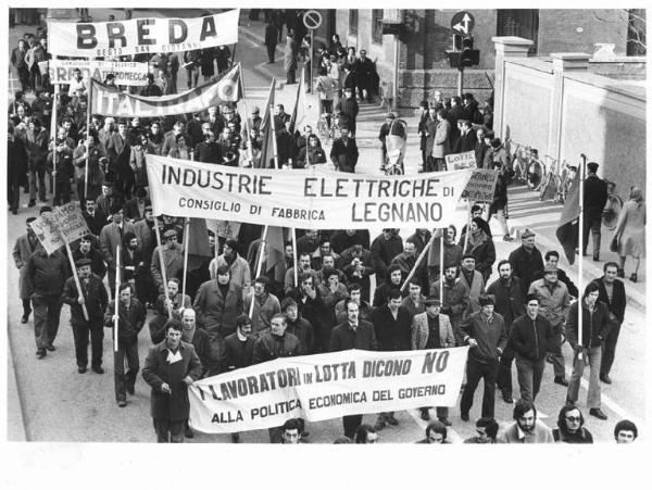 Sciopero elettromeccanici per lo sviluppo del settore - Corteo - Spezzone lavoratori delle industrie elettriche di Legnano e della Breda - Operai con tuta da lavoro - Passanti - Striscioni - Cartelli - Bandiere