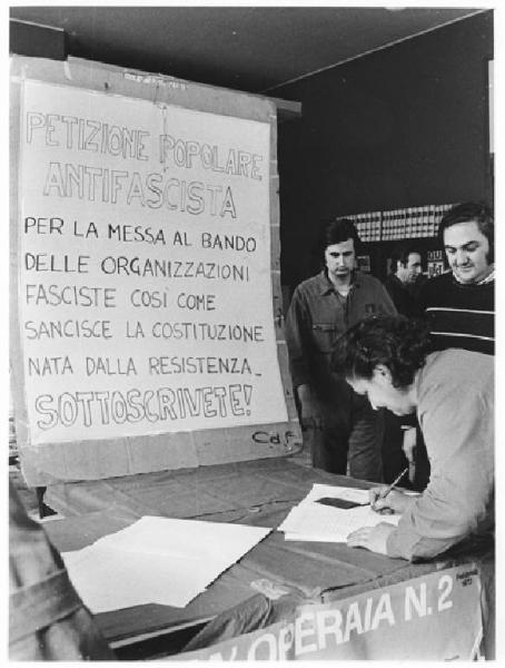 Imperial - Interno - Assemblea permanente dei lavoratori per il contratto - Banchetto con raccolta firme per petizione antifascista - Lavoratrice firma - Cartello della petizione