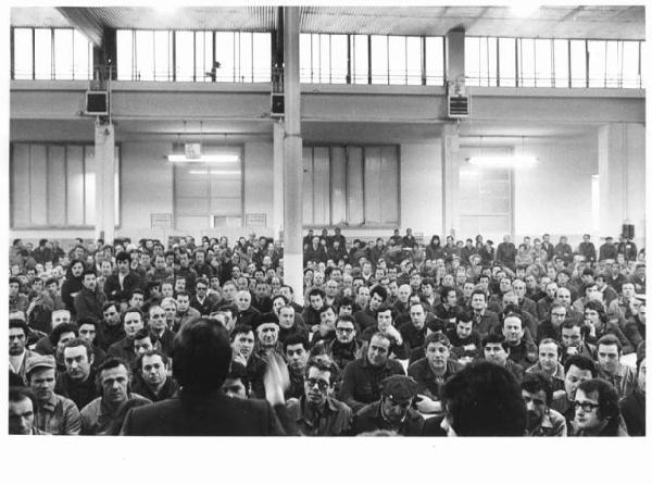 Innocenti - Capannone - Interno - Assemblea dei lavoratori per il contratto - Panoramica sulla sala - Giorgio Benvenuto di spalle al microfono - Operai con tuta da lavoro