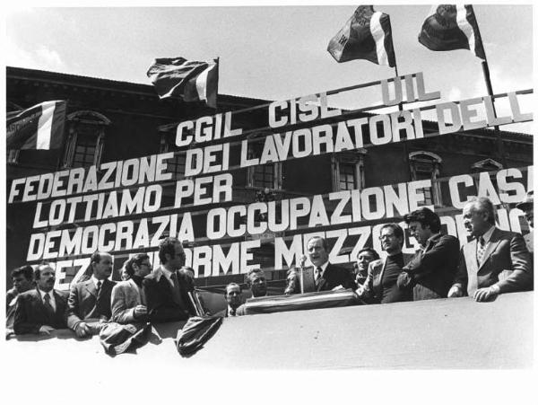 Sciopero nazionale dei lavoratori edili - Comizio in piazza San Giovanni - Palco - Bruno Storti, segretario generale Cisl, al microfono - Parola d'ordine - Bandiere