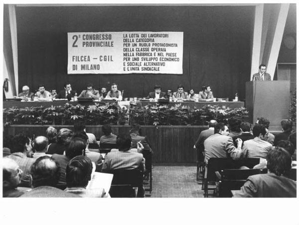 Camera del Lavoro - Salone "Di Vittorio" - Interno - Secondo congresso provinciale Filcea Cgil - Tavolo della presidenza con tra gli altri L. De Carlini, A. Japà - Luigi Nava al microfono - Parola d'ordine