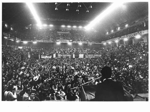 Palazzetto dello sport - Interno - Manifestazione per il Cile - Panoramica sulla sala - Mario Colombo di spalle al microfono - Platea con manifestanti - Striscioni