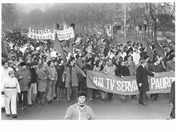 Sciopero dei lavoratori della Pirelli - Corteo in corso Sempione verso la Rai - Operai con tuta da lavoro - Striscione "Rai serva dei padroni" - Bandiere