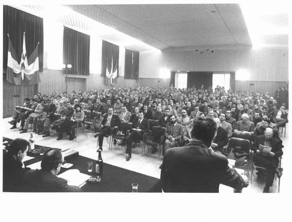 Convegno provinciale unitario edili - Interno - Panoramica sulla sala - Oratore al microfono - Platea - Bandiere