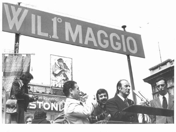 Festa dei lavoratori - Manifestazione del primo maggio - Comizio in piazza del Duomo - Palco - Raffaele Vanni, segretario nazionale, al microfono, al suo fianco Lucio De Carlini - Fotografi - Striscione "W il 1 maggio" - Pubblicità sui palazzi