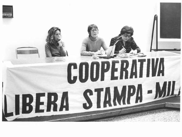 Assemblea della cooperativa Libera stampa - Interno - Tavolo della presidenza con oratrici - Striscione