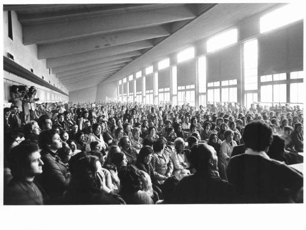 Imperial - Interno - Assemblea permanente in fabbrica contro la richiesta di cassa integrazione per mille lavoratori - Panoramica sulla sala - Platea - Operaie con grembiule da lavoro - Striscione