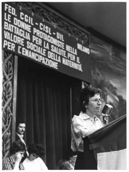 Convegno di Cgil, Cisl, Uil di Milano per la difesa della salute della lavoratrice - Interno - Palco - Flora Bocchio al microfono - Parola d'ordine