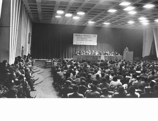 Camera del Lavoro - Salone "Di Vittorio" - Interno - Convegno provinciale Fiom - Panoramica sulla sala - Tavolo della presidenza - Antonio Pizzinato al microfono - Platea - Parola d'ordine - Bandiera Fiom