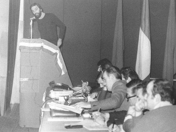 Conferenza unitaria Flm dei delegati di zona - Interno - Tavolo della presidenza - Oratore al microfono - Bandiera italiana