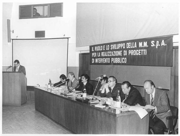 Sala - Interno - Convegno sindacale sui trasporti - Tavolo della presidenza, tra i relatori Leonardo Banfi - Oratore al microfono - Parola d'ordine