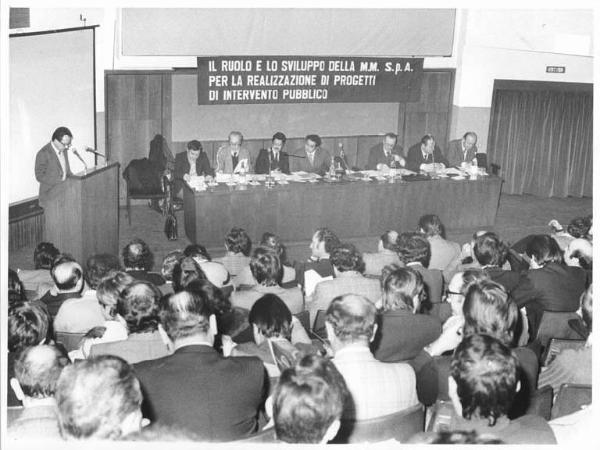 Sala - Interno - Convegno sindacale sui trasporti - Tavolo della presidenza, tra i relatori Leonardo Banfi - Oratore al microfono - Parola d'ordine