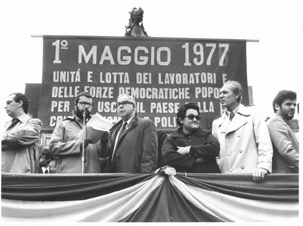 Festa dei lavoratori - Manifestazione del primo maggio - Comizio in Piazza del Duomo - Palco con Lucio De Carlini, Luigia Alberti, Leonardo Banfi - Oratore al microfono - Striscione con parola d'ordine