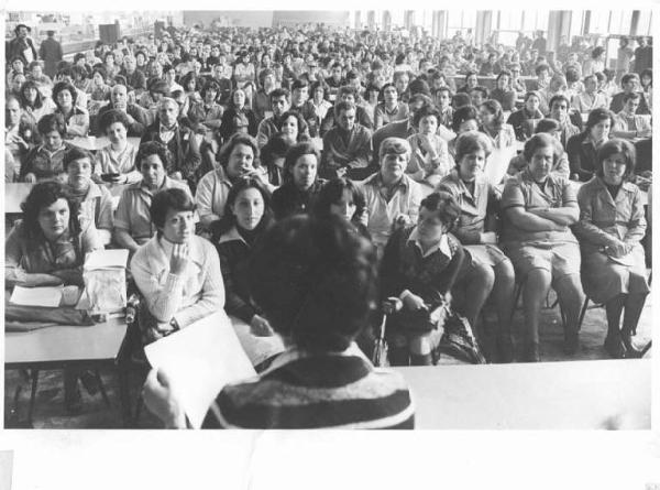 Fabbrica Imperial - Interno - Assemblea aperta dei lavoratori per l'occupazione - Panoramica sulla sala - Operaie con grembiule da lavoro - Oratrice di spalle