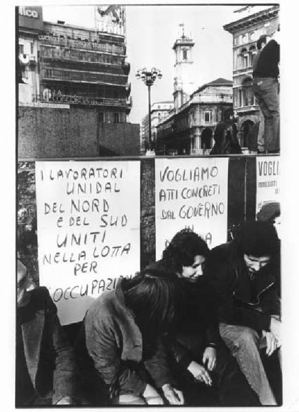 Sciopero dei lavoratori della Unidal - Presidio in piazza del Duomo - Lavoratori seduti sul monumento a Vittorio Emanuele II - Cartelli di protesta