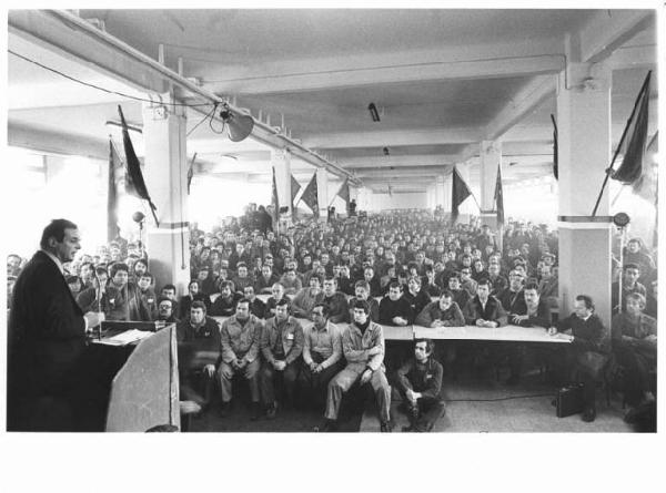 Fabbrica Ercole Marelli - Interno - Assemblea dei lavoratori - Panoramica sulla sala - Luciano Lama al microfono - Platea - Operai con tuta da lavoro - Bandiere Flm