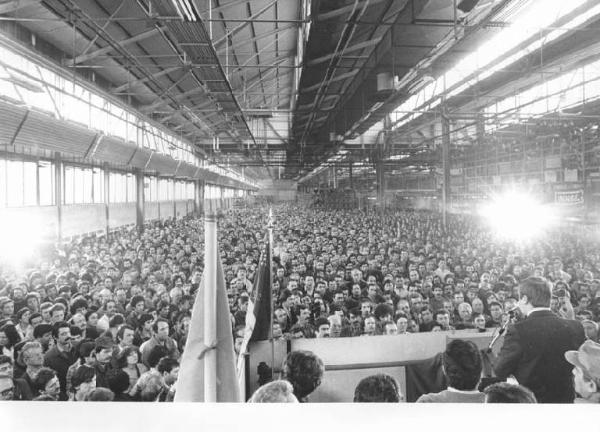 Fabbrica Alfa Romeo di Arese - Capannone - Interno - Celebrazione del 25 aprile - Panoramica - Platea con gli operai - Giorgio Benvenuto di spalle al microfono - Bandiera