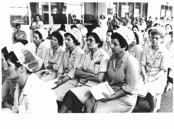 Fabbrica Ferrero - Interno - Assemblea dei lavoratori per l'approvazione del contratto - Platea - Operaie con grembiule da lavoro e cuffietta