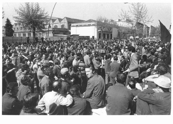 Celebrazione del 30° anniversario della Liberazione - Comizio davanti alla fabbrica Breda - Oratore al microfono - Operai con tuta da lavoro - Bandiera