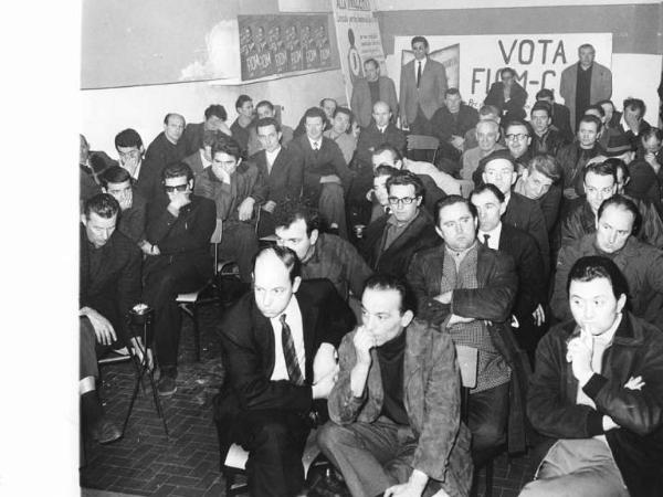 Innocenti - Interno della fabbrica - Assemblea unitaria (Fiom, Fim, Uilm) dei lavoratori del reparto meccanico - Platea - Lavoratori - Manifesti