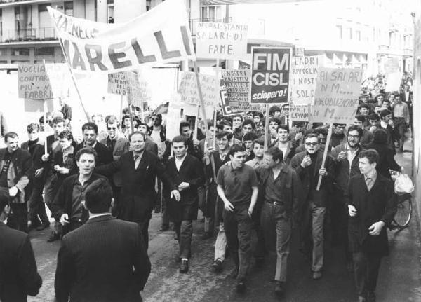 Sciopero dei lavoratori della Magneti Marelli - Corteo - Operai con grembiule da lavoro - Striscione - Cartelli di protesta - Cartelli di sciopero Fim Cisl, Fiom Cgil