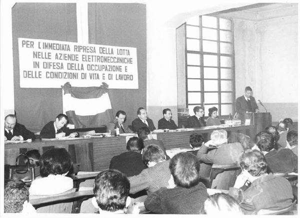 Camera del Lavoro - Sala "Bruno Buozzi" - Interno - Convegno Fiom settore elettromeccanici - Tavolo della presidenza - Al microfono Bruno Trentin - Parola d'ordine del convegno