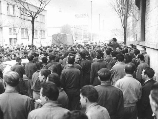 Sciopero dei lavoratori dell'Alfa Romeo - Stabilimento del Portello - Comizio davanti alla fabbrica - Oratore al microfono - Operai con tuta da lavoro - Insegna Alfa Romeo