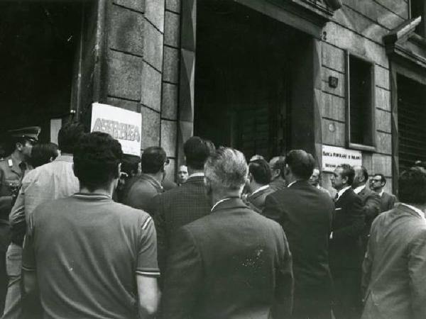 Assemblea degli impiegati della Falck - Un gruppo di persone legge il cartello che annuncia l'assemblea