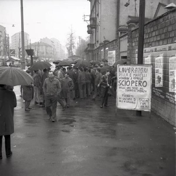 Sciopero dei lavoratori della Ercole Marelli - Ingresso della fabbrica - Presidio sotto la pioggia - Operai con tuta da lavoro - Cartello di protesta Fiom Fim Uilm