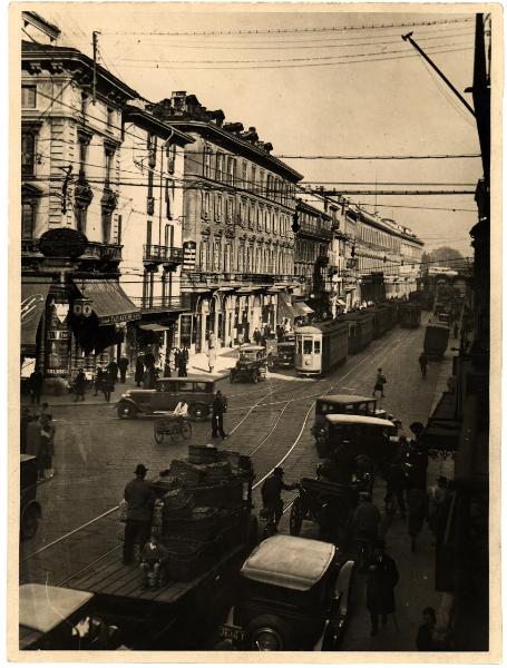 Milano - Via Manzoni. Veduta della via in un momento di traffico con tram, auto, bici e carri. Vigile.