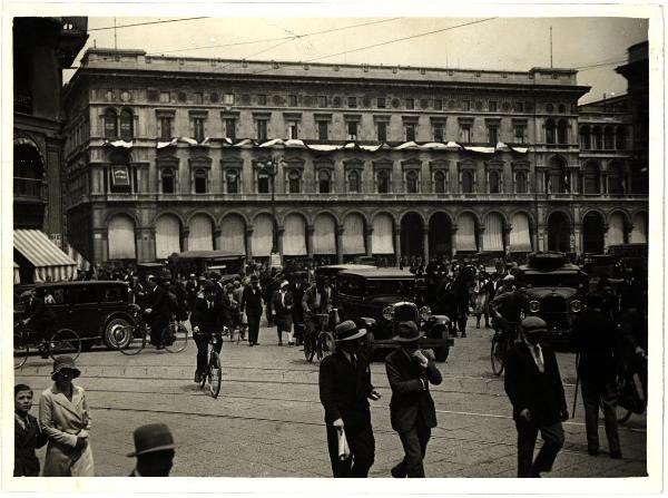 Milano - Piazza del Duomo. Traffico di tram, auto e persone a piedi e in bicicletta nella piazza all'angolo con via Orefici.