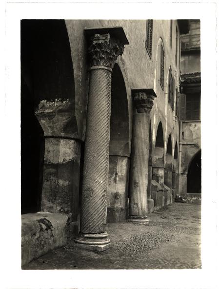 Novara - Chiostro della Canonica del Duomo. Veduta di scorcio di due colonne con capitelli romani dell'antico Duomo addossate ai pilastri ottogonali del portico.