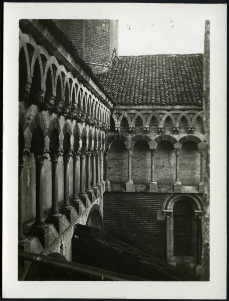 Vercelli - Basilica di S. Andrea. Particolare della decorazione della facciata laterale ad archetti incrociati retti da mensole con teste scolpite e sottostante galleria ad archi.