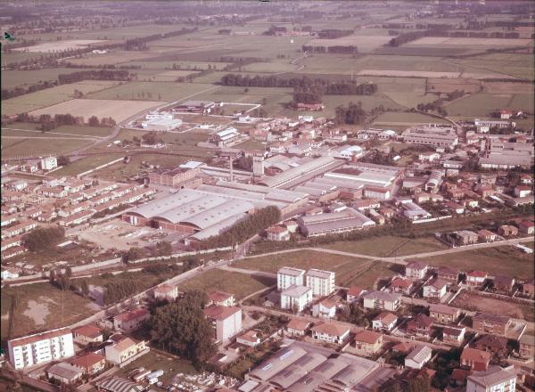 Campagna lombarda. Abbiategrasso ?. Capannoni industriali. Cascinale con torre passeriaia. Veduta aerea.