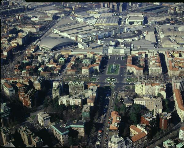 Milano. Piazzale Giulio Cesare. Via Michelangelo Buonarroti. Fontana delle Quattro Stagioni. Sullo sfondo la fiera di Milano e la porta Giulio Cesare. Veduta aerea.