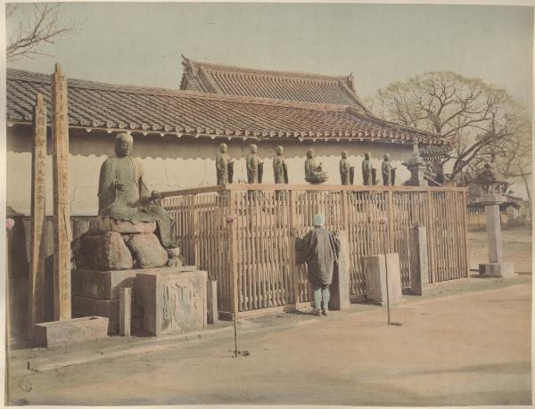 Giappone - Santuario - Piattaforma con statue di Buddha circondata da una staccionata - Statua di Buddha più grande su un basamento - Uomo guarda attraverso la palizzata