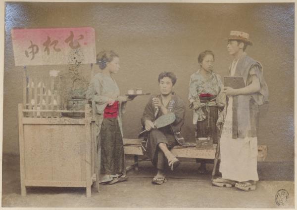 Giappone - Scena di genere - Interno di una casa da té - Banchetto di servizio con iscrizione ideografica - Una donna serve del té a due uomini - Una seconda donna è in piedi accanto ad uno degli astanti