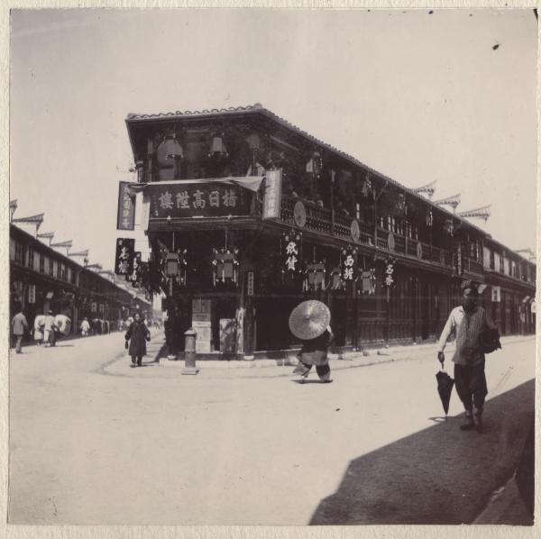 Shanghai - Strada della città - Nanjing road - Edificio d'angolo con lanterne cinesi e scritte in ideogrammi - Passanti con ombrellini