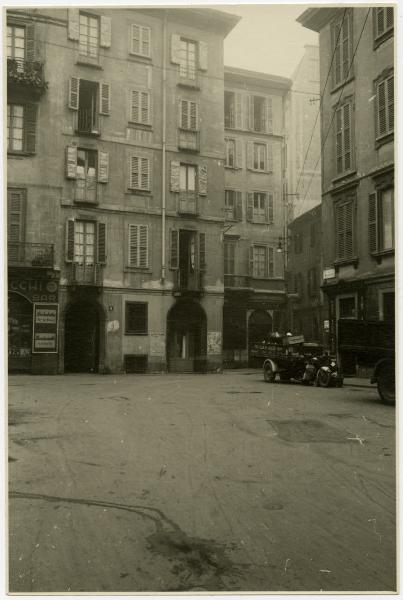 Milano - Piazza Pasquirolo imbocco di Via S. Zeno // insegne negozi, motocarro con parafanghi bianchi (probabile moto Guzzi Ercole)