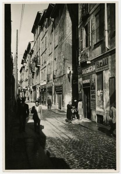 Milano - Via Paolo da Cannobio, angolo Via Bottonuto - Negozi "Negozio Magnifico", "Trattoria Toscana Maltagliati" e "Drogheria Profumerie", cartellone pubblicitario "Brill la perla dei lucidi - Passanti - Campanile di San Gottardo in Corte