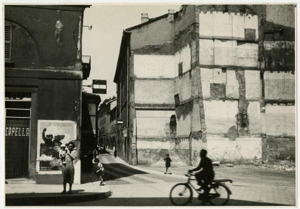 Milano - Imbocco via Pioppette da via della Chiusa - Negozio "Fattorie Riunite Capella e C., latteria" (?), manifesto celebrativo del quarto anniversario della proclamazione della sovranità italiana sull'Etiopia (9 maggio 1936), passanti