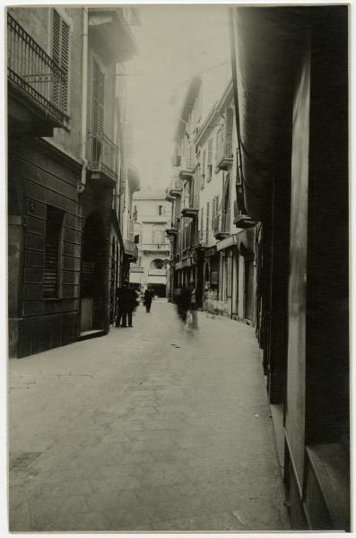 Milano - Via S. Maurilio verso via Torino - Insegne di negozi su via Torino Profumeria e Casa dell'abito, passanti