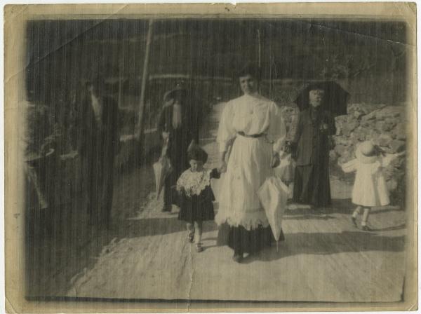 Ritratto di gruppo - Elvira Lazzaroni e la madre Teresa con altra donna, uomo e tre bambini - Esterno, strada - Campi coltivati