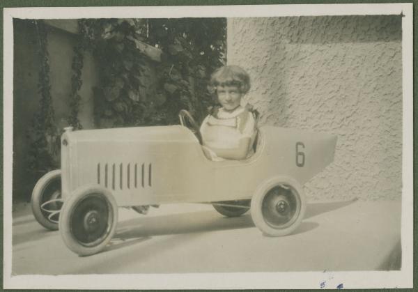 Ritratto infantile - Bambina dentro automobile da corsa giocattolo - Ravenna - Abitazione, cortile