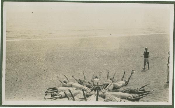 Ritratto di gruppo - Marieda di Stefano e altre persone sdraiate sulla spiaggia in cerchio con le braccia alzate - Finale Ligure, Varigotti